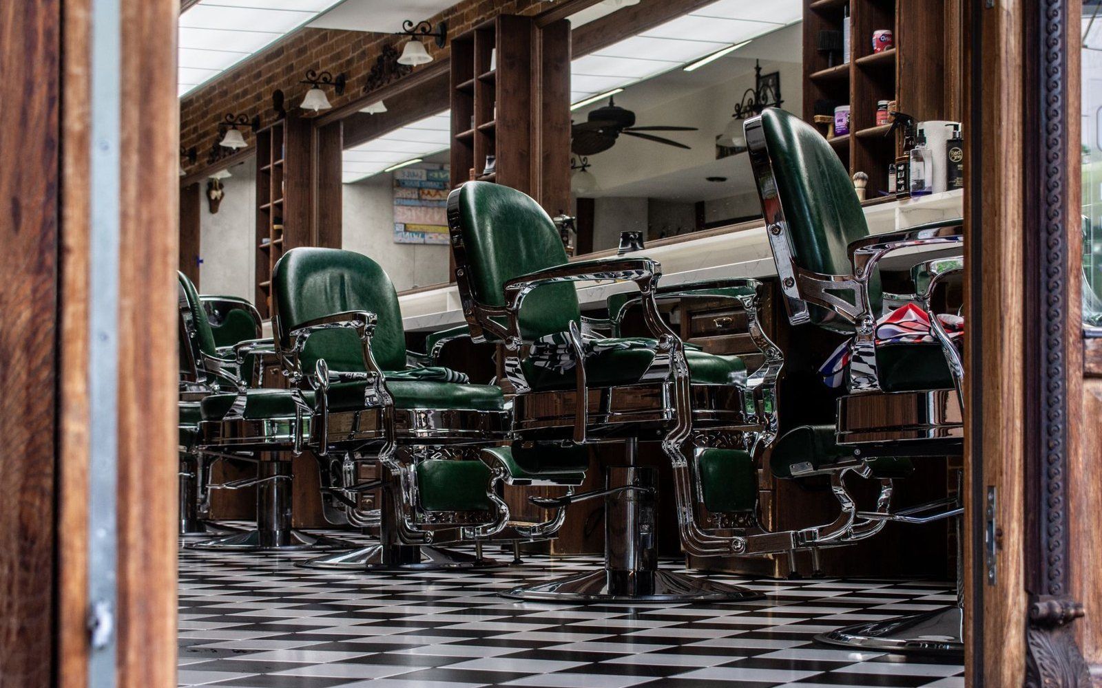 Barber shop con le poltrone verdi in fila e il pavimento a scacchi